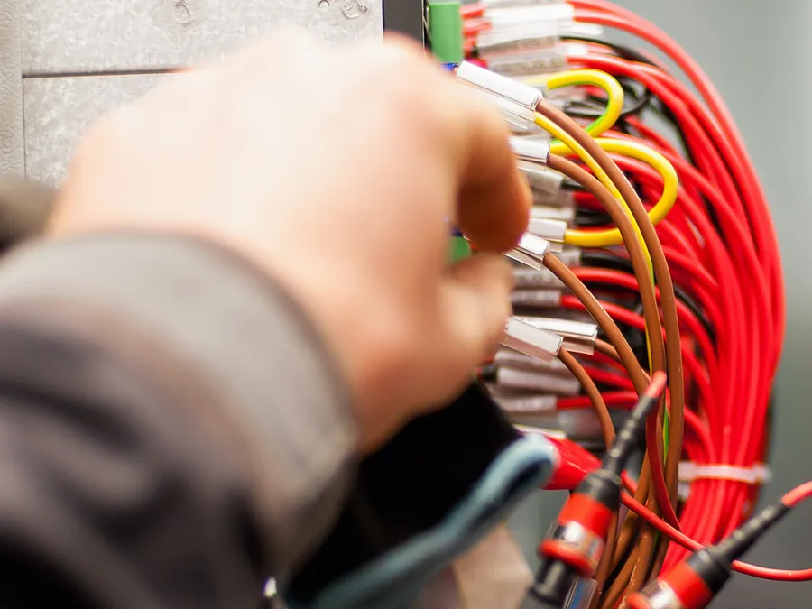 An M Electrical engineer terminating cables inside a control panel