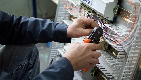 An electrician wiring a commercial distribution panel