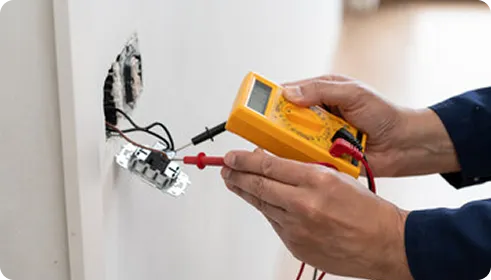 An electrician testing a socket outlet with a multimeter
